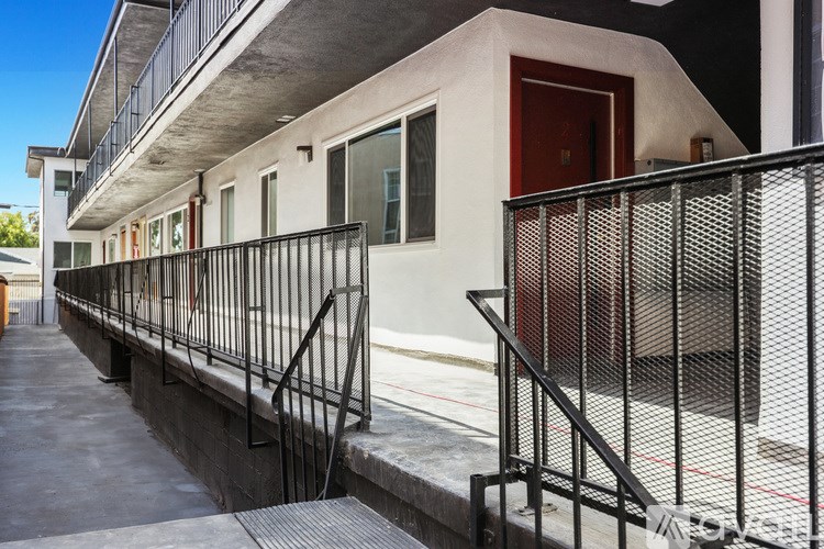 A building with a red door and a balcony with a black railing.
