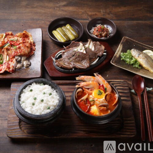 A wooden table with a variety of Korean dishes including rice, kimchi, and fish.