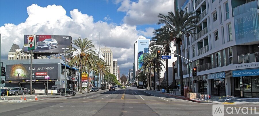 A street view of a city with palm trees and billboards.