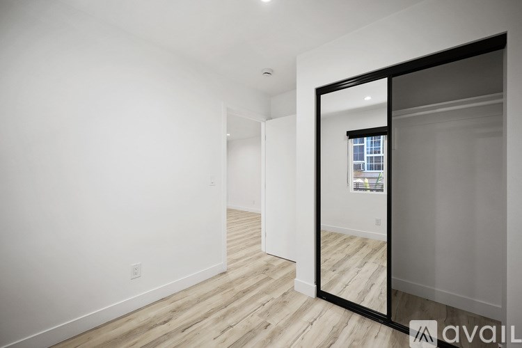 A room with a mirror on the wall reflecting a window.