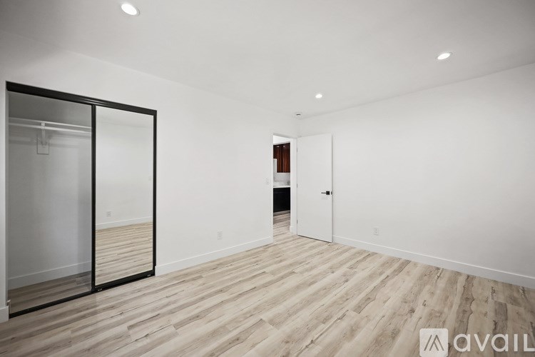 A room with wooden flooring and a white wall with a door and a glass door.