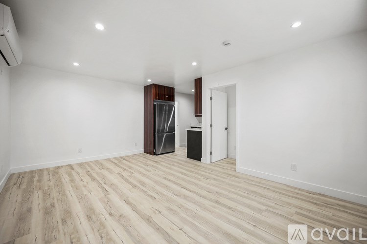 A spacious room with wooden flooring and white walls.