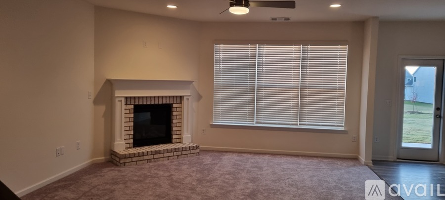 A living room with a fireplace and a window with blinds.