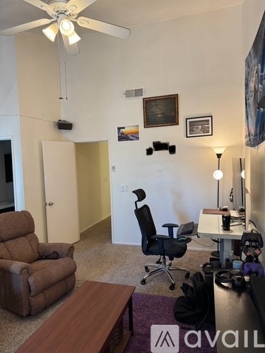 A room with a brown recliner, a desk, and a ceiling fan.