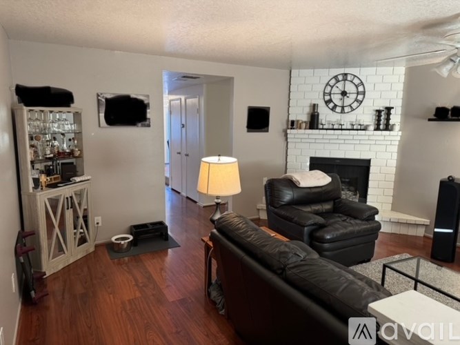 A living room with a black leather couch and a fireplace.