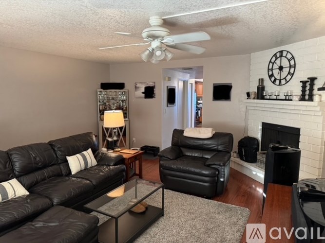 A living room with a black leather couch and a fireplace.