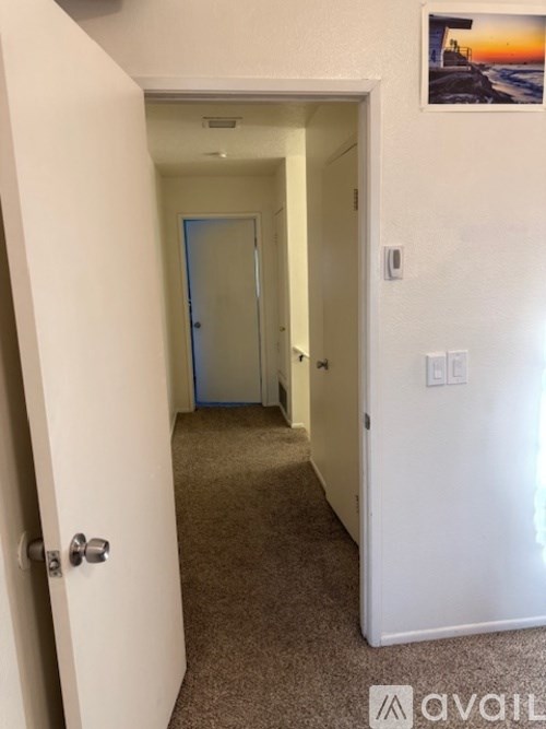 A hallway with a carpeted floor and a door at the end.