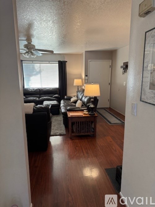 A living room with a black leather couch and a wooden coffee table.