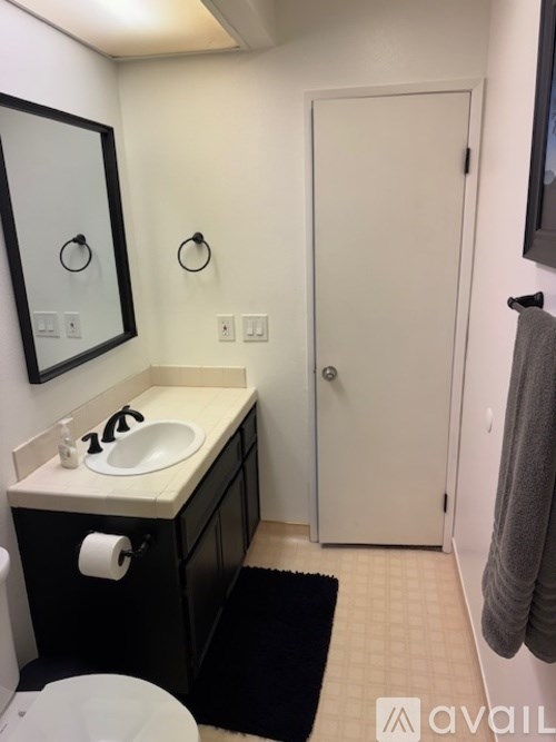 A bathroom with a sink, mirror, toilet and a door.