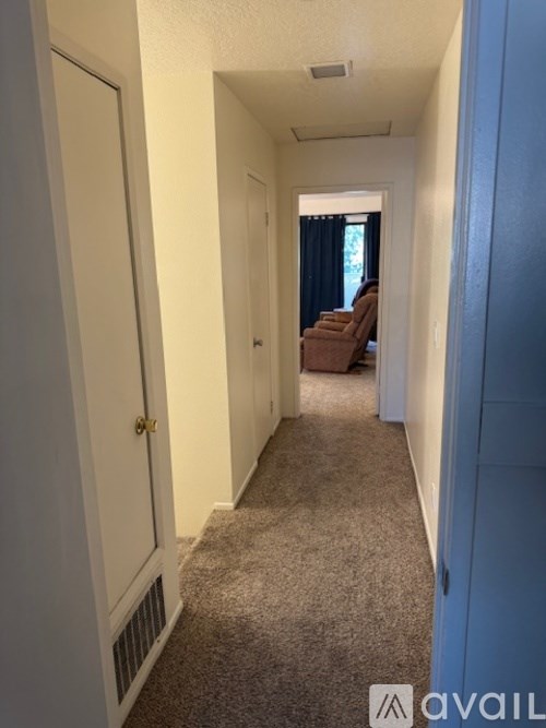 A hallway with a carpeted floor and a door on the left.