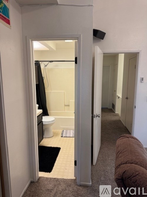 A bathroom with a toilet and a shower is visible through an open door.