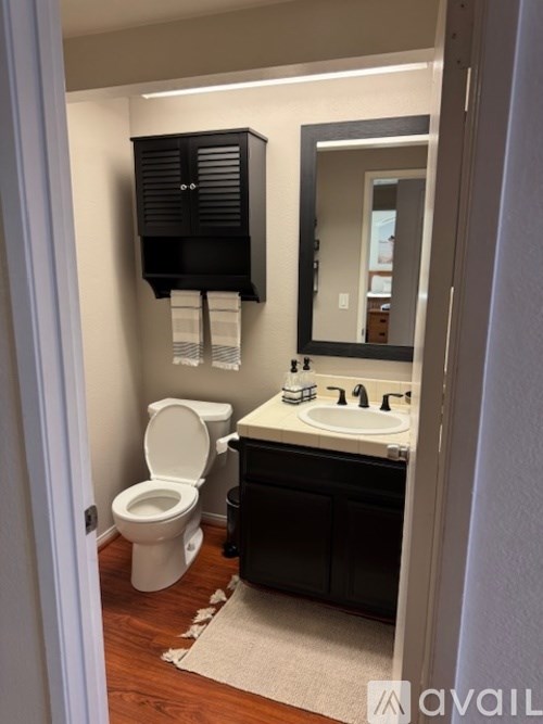 A bathroom with a toilet, sink, and mirror.