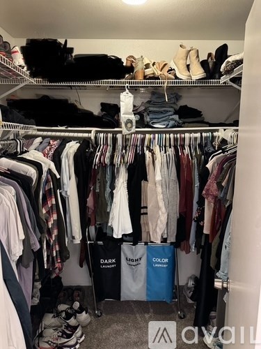 A cluttered closet with clothes and shoes on shelves and hangers.