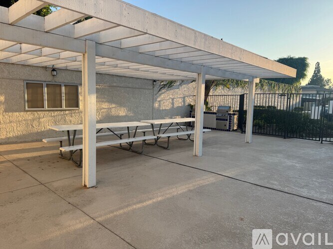 A patio area with a white pergola and a bench.