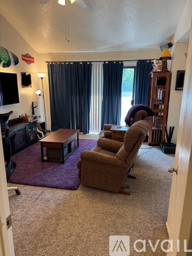 A living room with a brown couch, a coffee table, and a television.