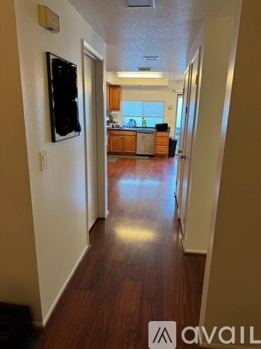 A hallway with a TV on the wall and a kitchen in the distance.