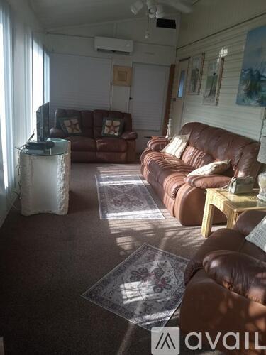A living room with brown leather couches and a rug.