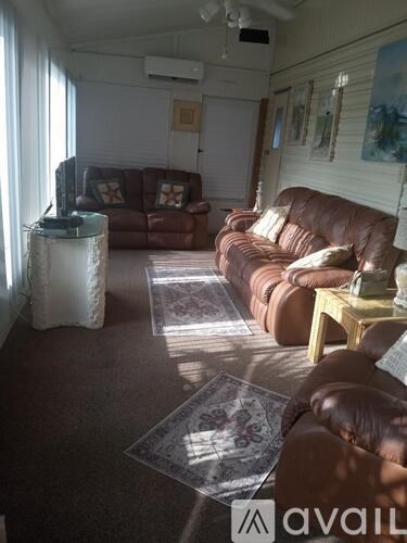 A living room with brown leather couches and a rug.