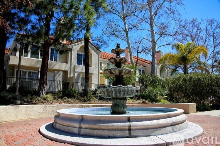 A fountain in the middle of a courtyard with a building in the background.