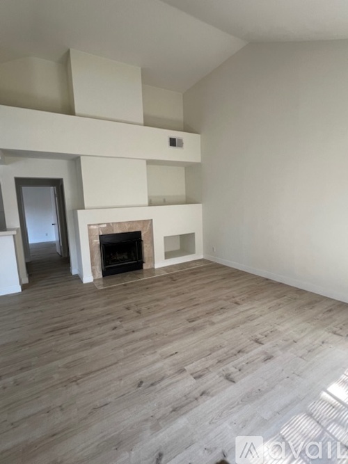 A living room with a fireplace and wooden floors.