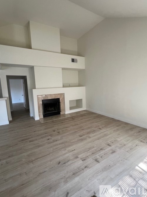 A living room with a fireplace and wooden floors.
