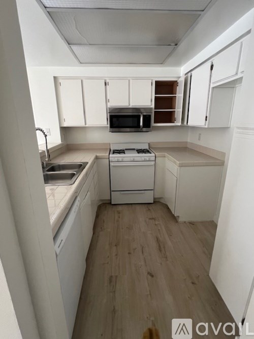 A kitchen with white cabinets and a white stove top oven.