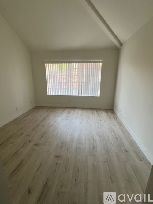 A room with wooden flooring and a window with blinds.