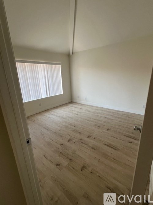 A room with wooden flooring and a window with blinds.