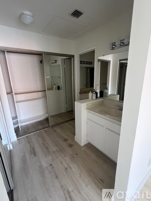 A bathroom with a sink, mirror, and a large window with blinds.
