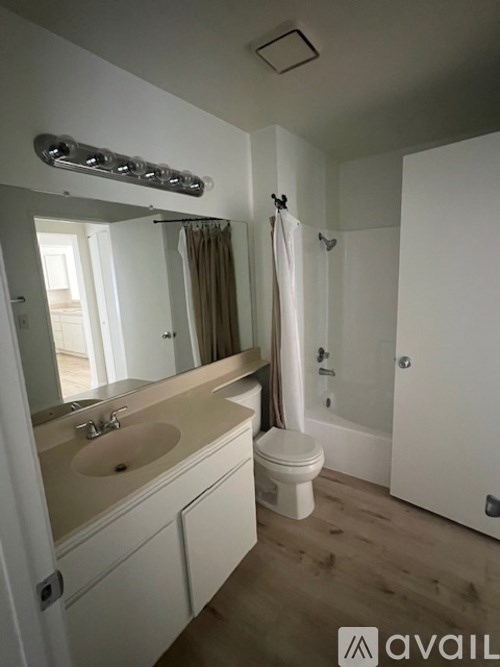 A bathroom with a white sink, toilet, and a white shower curtain.