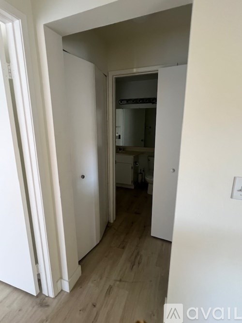 A hallway with a door on the left and a kitchen in the distance.