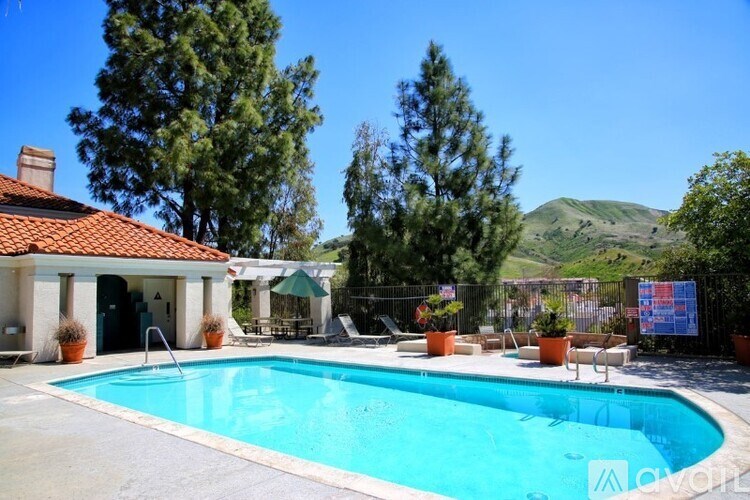A pool in a backyard with a house and trees in the background.
