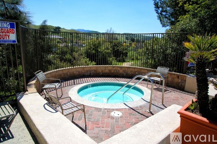 A hot tub sits on a patio with a pool guard duty sign in the background.