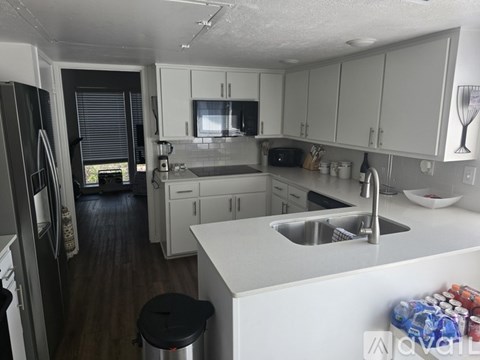 A kitchen with white cabinets and a black stool.