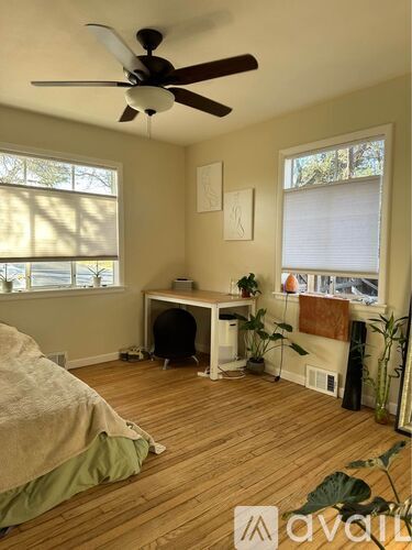 A room with a bed, desk, and a ceiling fan.