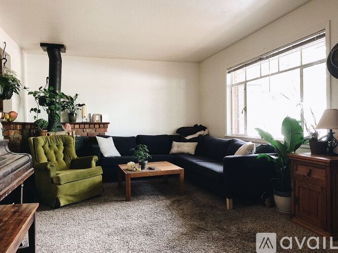 A living room with a green armchair, a black couch, and a wooden coffee table.
