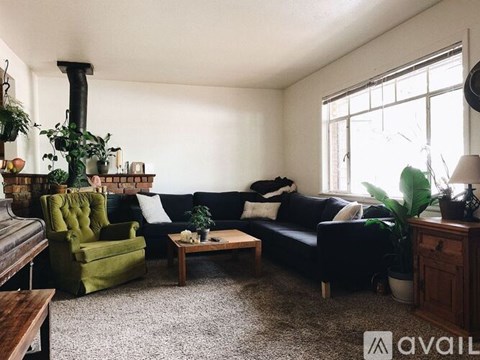 A living room with a green armchair, a black couch, and a wooden coffee table.