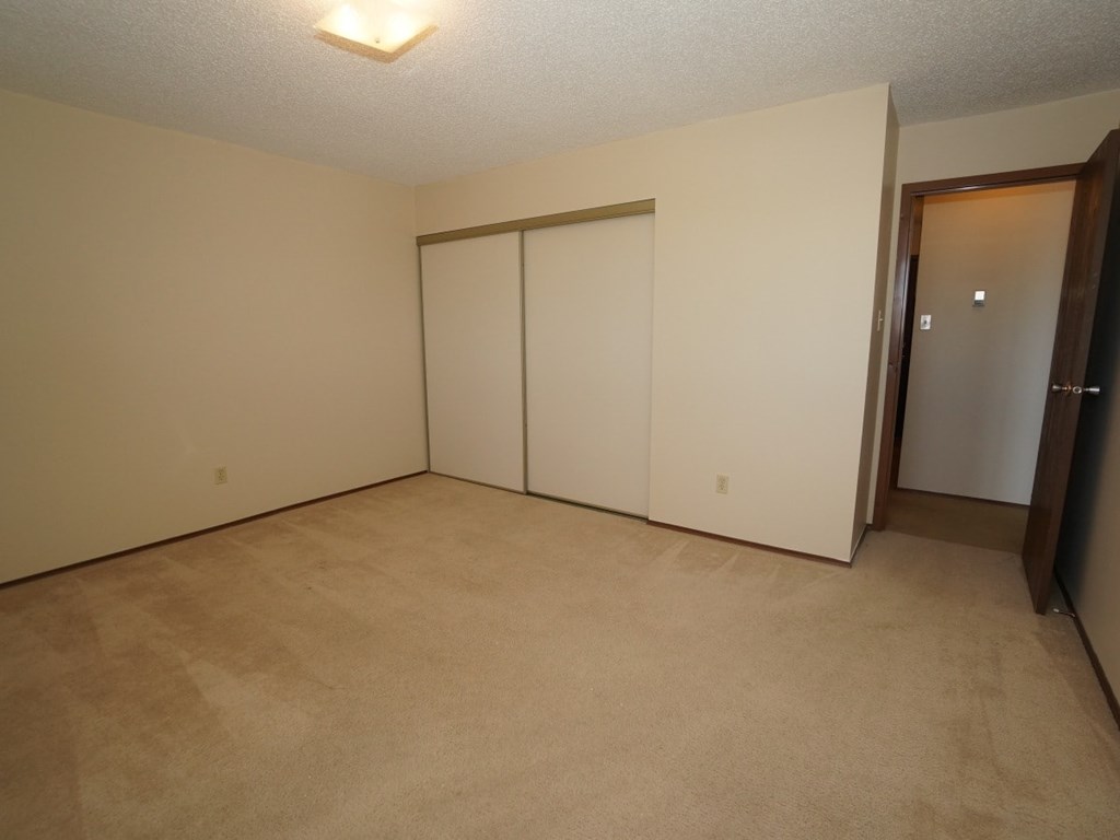 A room with a carpeted floor and a white door.