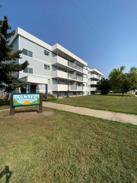 A Sunset Manor apartment complex with a sign in front.