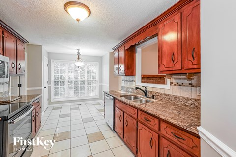 A kitchen with brown cabinets and a tiled floor.