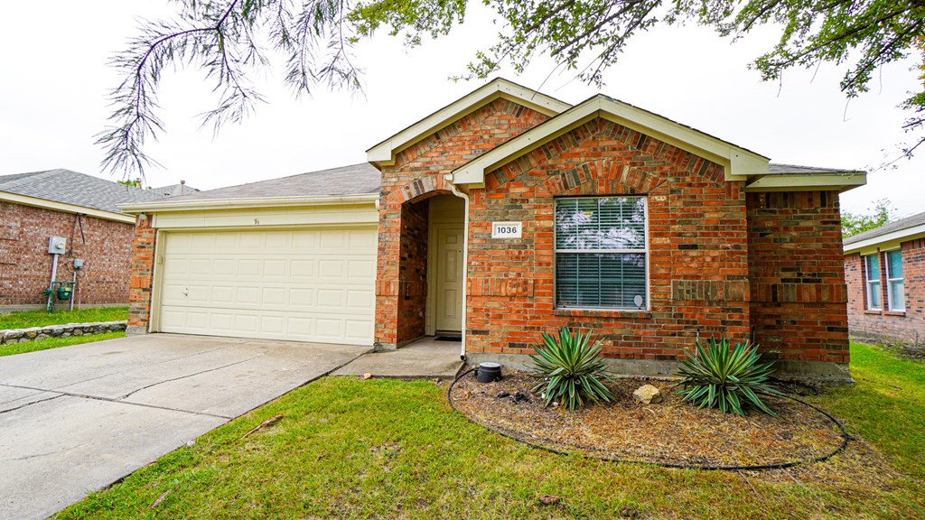A red brick house with a white garage door and a window with blinds.
