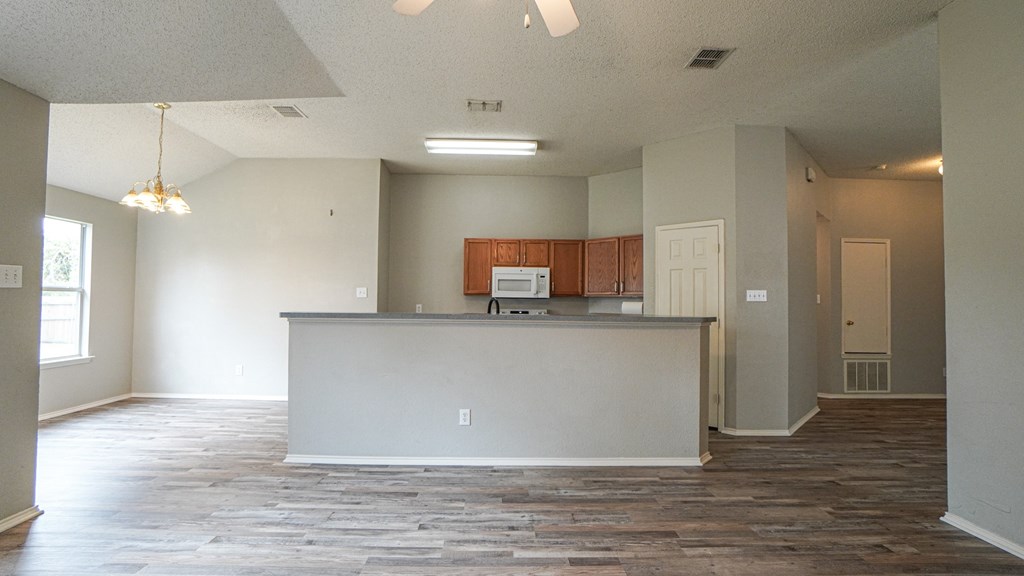 A spacious office with a white reception desk and a wood grain floor.