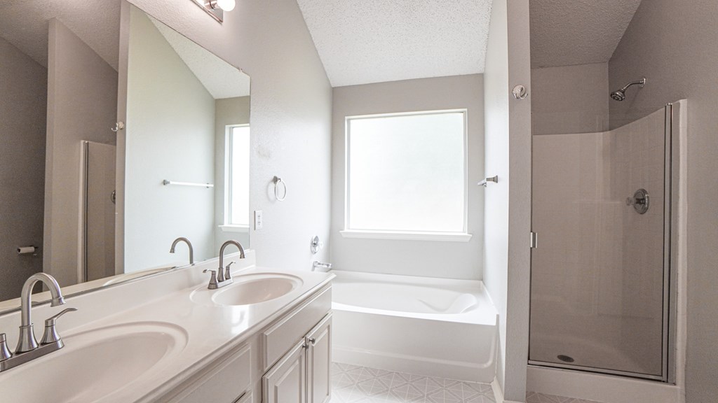 A white bathroom with a sink, mirror, and bathtub.