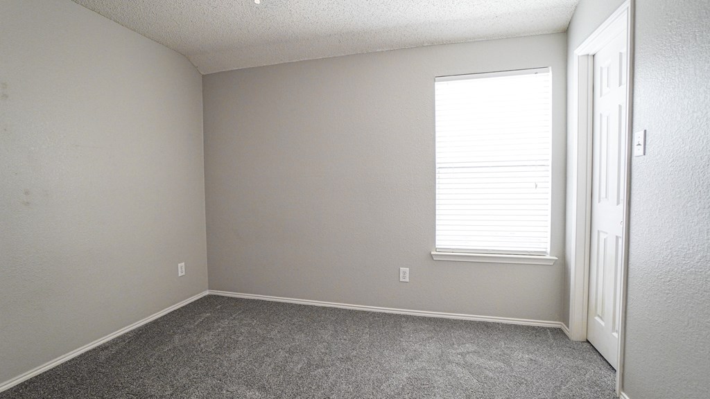 A room with a door and a window with blinds.