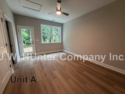A room with wooden flooring and a window with a view of trees.