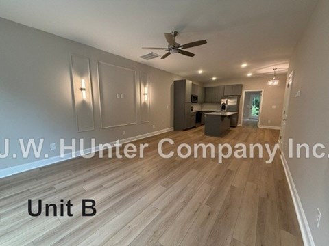 A spacious room with wood flooring and a ceiling fan, labeled as Unit B.