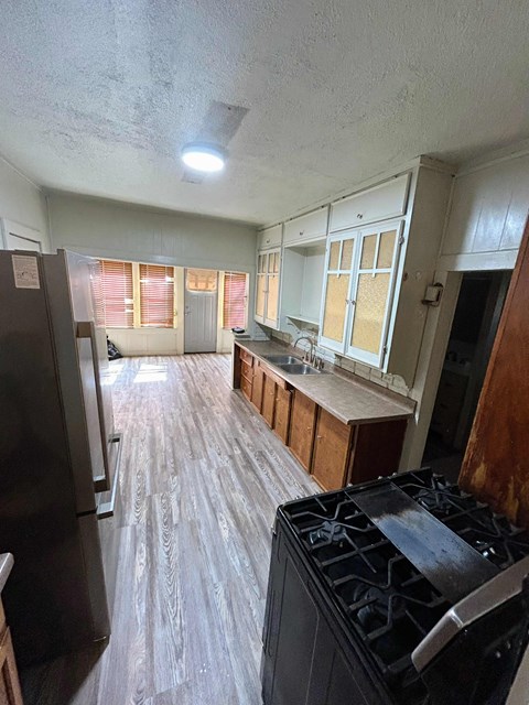A kitchen with a black stove top oven and wooden flooring.