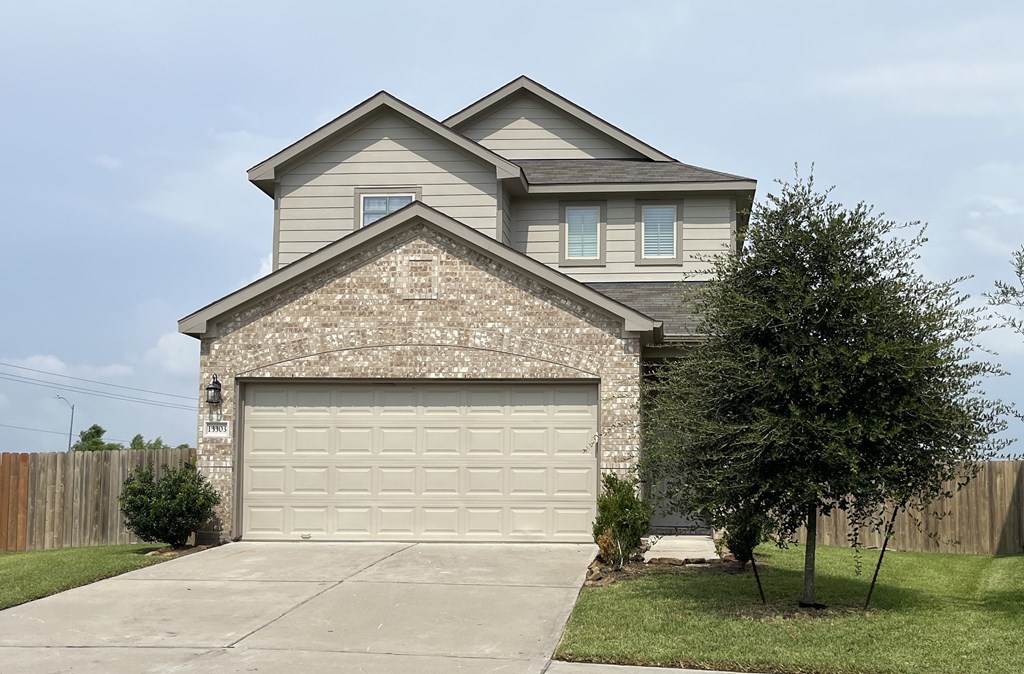 A house with a garage and a tree in front.
