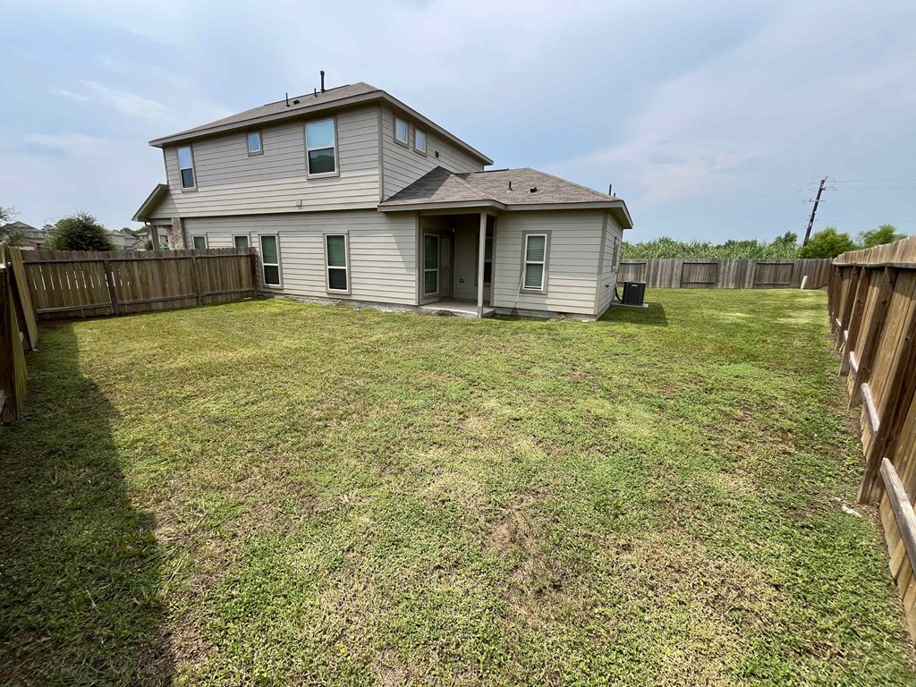 A house with a grey roof and a fenced backyard.