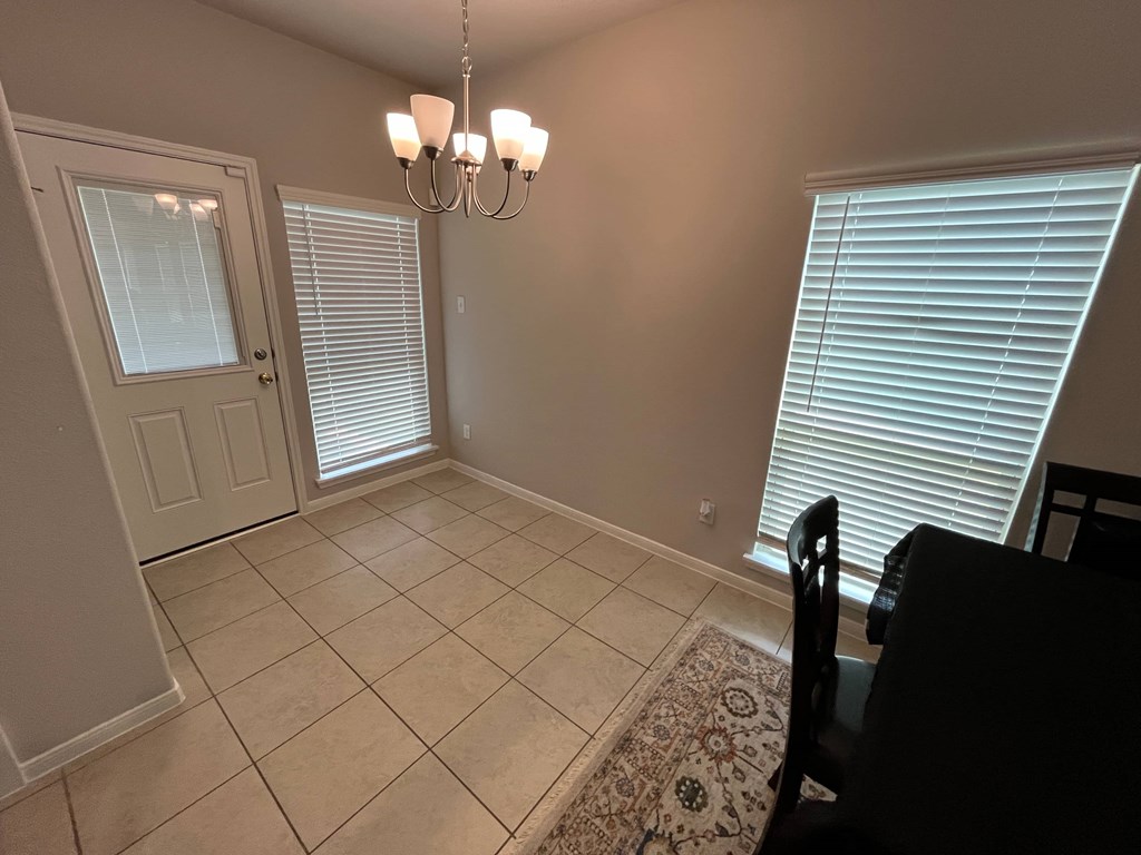 A room with a chandelier, a door, and a window with blinds.